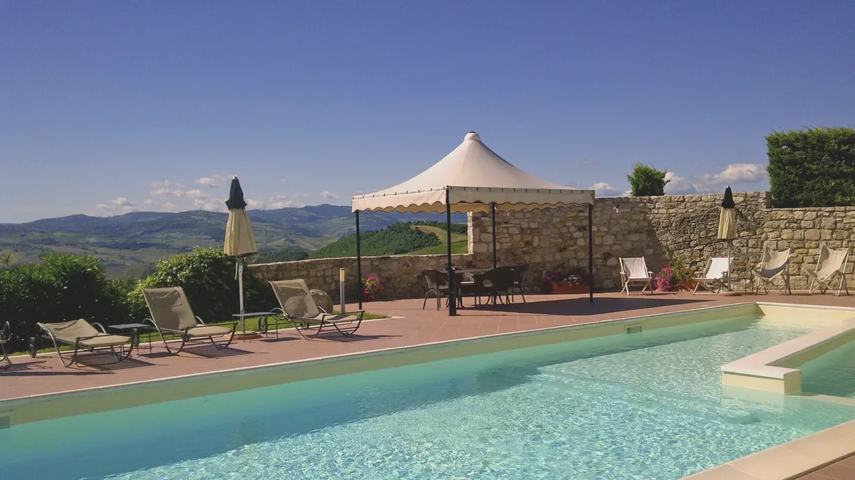 Gazebo bianco a bordo piscina con colline
