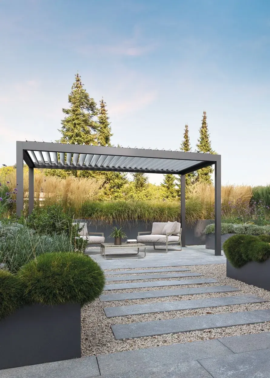 Pergola bioclimatica Movie grigio antracite in un giardino con salotto da esterno