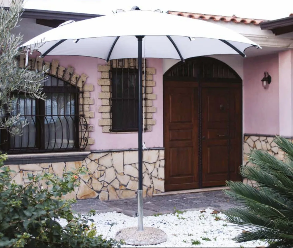 Ombrellone ottagonale bianco davanti a una casa in pietra